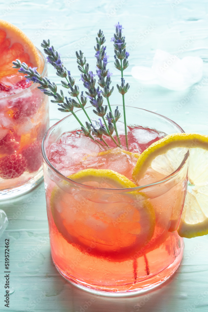 Summer cocktail or mocktail, cold drink with lemon and lavender, party lemonade with ice on a blue background, a close-up Summer cocktail or mocktail, cold drink with lemon and lavender, party lemonade with ice on a blue background, a close-up