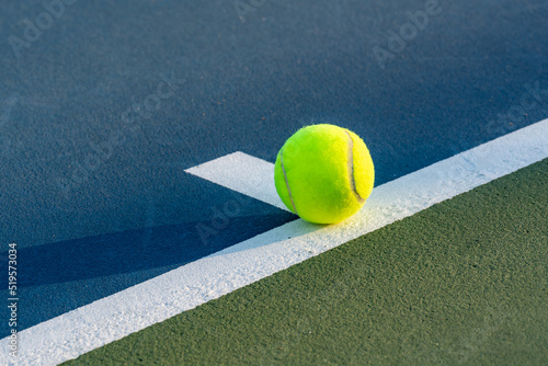 Yellow tennis ball on baseline at center mark on a new blue tennis court with green out of bounds  © Thomas