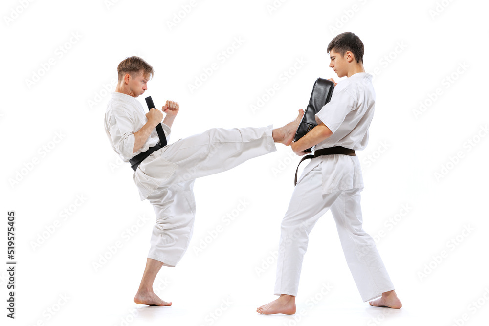 Two athletes, karate-do fighters in doboks practicing karate isolated on white background. Concept of sport, education, skills, martial arts, healthy lifestyle Two athletes, karate-do fighters in doboks practicing karate isolated on white background. Concept of sport, education, skills, martial arts, healthy lifestyle