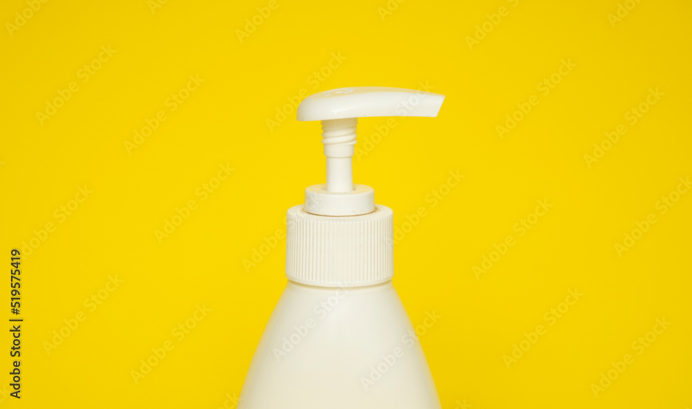 White plastic soap or shampoo dispenser pump bottle isolated on yellow background. Skin care lotion. Bathing essential product. Shampoo bottle. Bath and body lotion. Fine liquid hand wash. White plastic soap or shampoo dispenser pump bottle isolated on yellow background. Skin care lotion. Bathing essential product. Shampoo bottle. Bath and body lotion. Fine liquid hand wash.