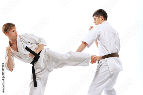 Two athletes, karate-do fighters in doboks practicing karate isolated on white background. Concept of sport, education, skills, martial arts, healthy lifestyle