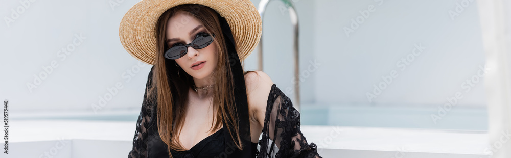 Fashionable woman in swimsuit and straw hat looking at camera at resort, banner. Fashionable woman in swimsuit and straw hat looking at camera at resort, banner.