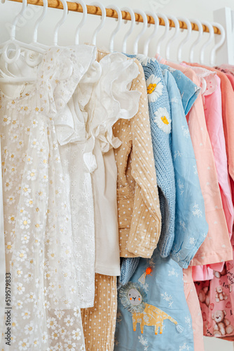 Clothing Rack with children's outfits close up. Home kids wardrobe. Nursery Storage Ideas. Baby Girl Clothes. © igishevamaria