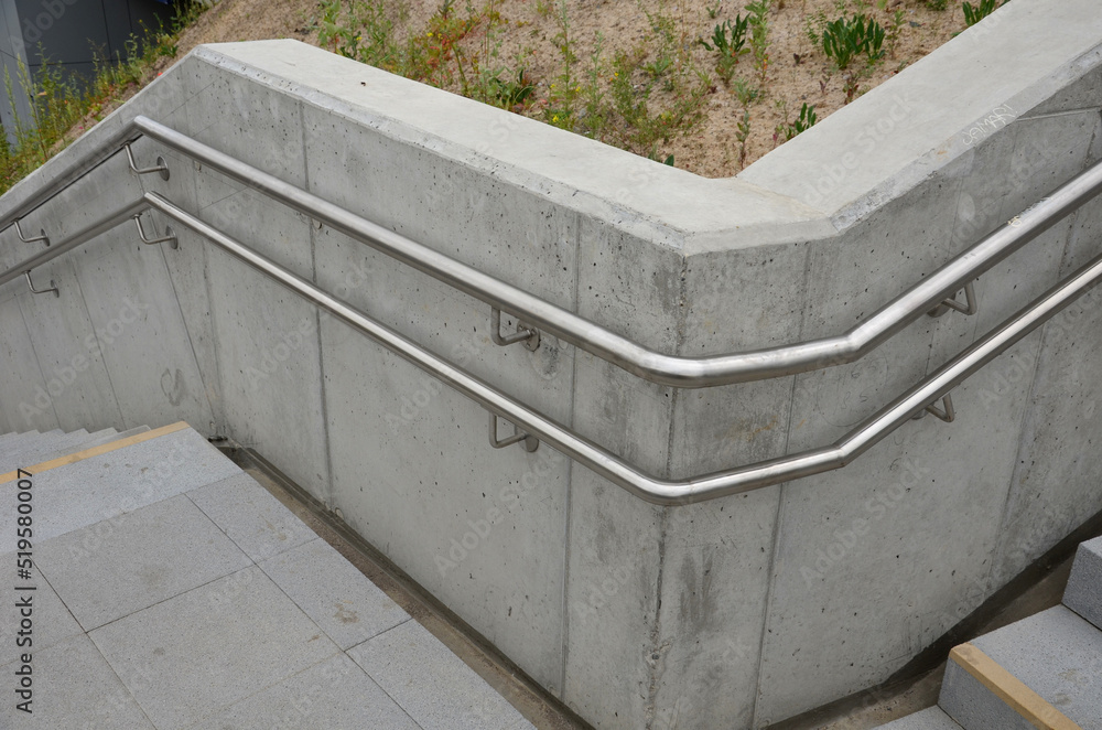 a staircase with concrete sides at a public building. the safe staircase has two handrails, one with a reduced height for children under 12 at the entrance to the school a staircase with concrete sides at a public building. the safe staircase has two handrails, one with a reduced height for children under 12 at the entrance to the school