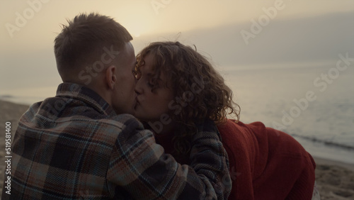 Romantic couple kissing on beach at sunrise. Girl and guy hugging each other