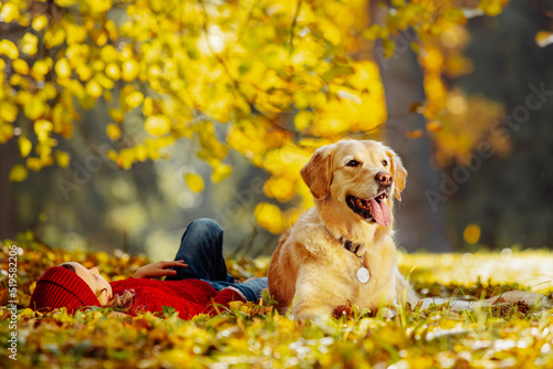 Friendly relationship between child and dog. Warm colors of autumn in the park.