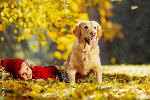 Carefree childhood and the Child lies on the warm autumn leaves next to his dog