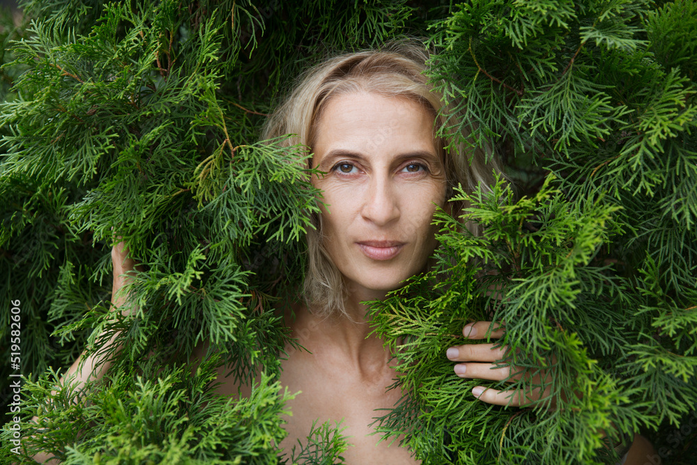 Profile of a enjoying nature middle aged woman to stand in thuja branches breathing fresh air. celebrate earth's day. Aromatherapy and Spa concept. ecology. climate change Profile of a enjoying nature middle aged woman to stand in thuja branches breathing fresh air. celebrate earth's day. Aromatherapy and Spa concept. ecology. climate change