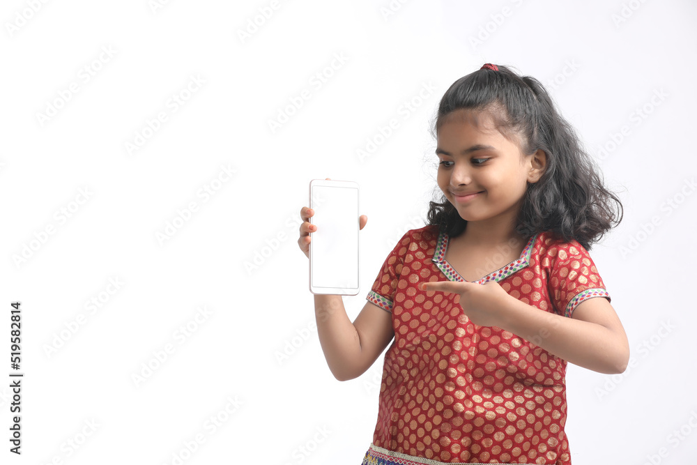 Cute indian little girl showing smartphone on white background Cute indian little girl showing smartphone on white background