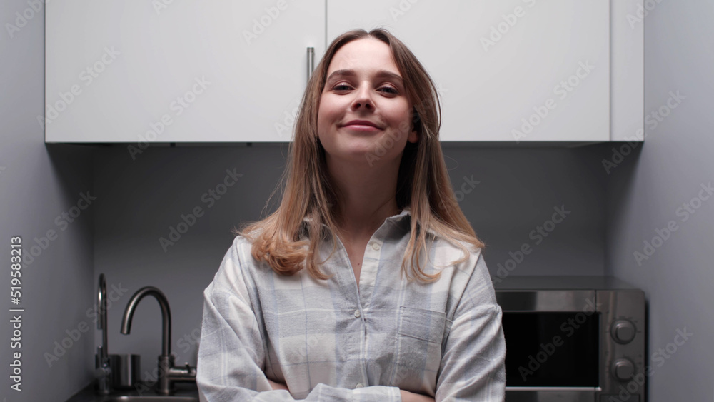 Portrait of young woman in pajamas look at camera standing in kitchen Portrait of young woman in pajamas look at camera standing in kitchen