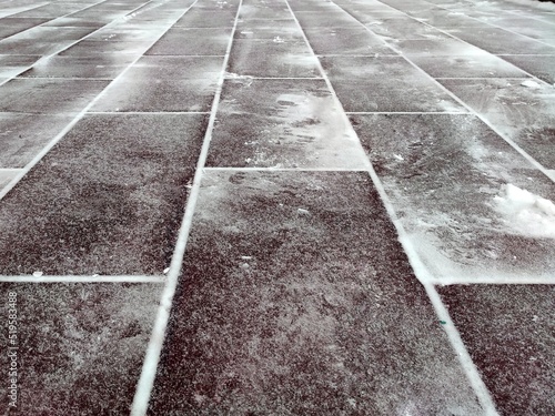 Tiled sidewalk, vertical "Brick" layout, a little snow-covered. Photo in gray tones for background. Horizontal photo 