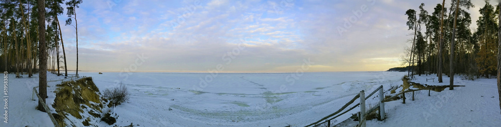 Panoramic photo. Winter river bank. Sunset over the river. 