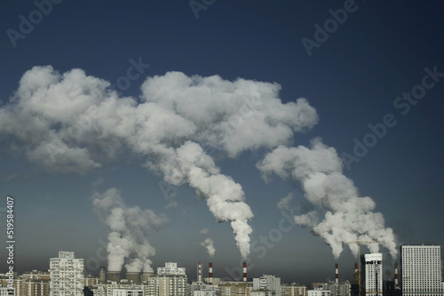 Thermal power plant, cooling towers, smoking chimneys against the blue sky and city smog. Cityscape - industrial area