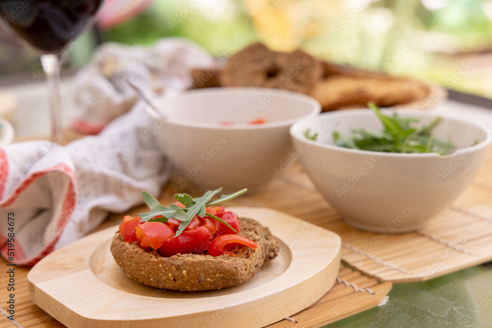 Tipical summer south Italian appetizer Friselle with cherry tomatoes, oil and rucola served outdoor Tipical summer south Italian appetizer Friselle with cherry tomatoes, oil and rucola served outdoor