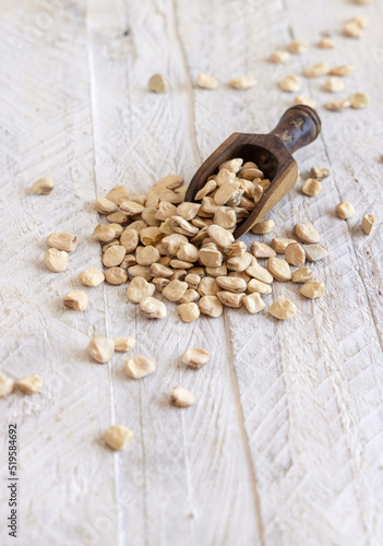 Scoop of raw dry Grass pea close up on wooden table. Legumes known in Italy as Cicerchia