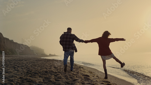 Loving couple walking on beach. Happy girl and guy enjoying summer sunset at sea