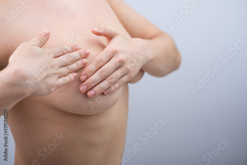 Caucasian woman self checks for breast cancer on white background. Copy space. 