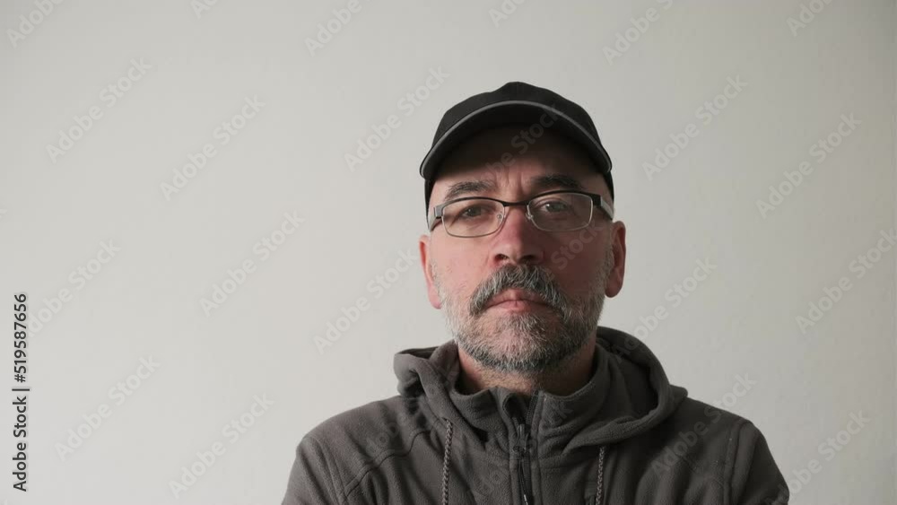 Bearded man in a cap and glasses on a white background in the studio looking at the camera and smiles. Bearded man in a cap and glasses on a white background in the studio looking at the camera and smiles.