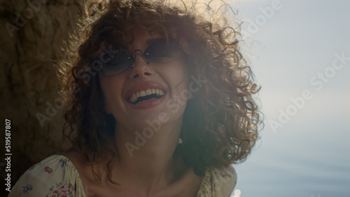 Slika na platnu Laughing girl shaking head sitting beach in front ocean close up