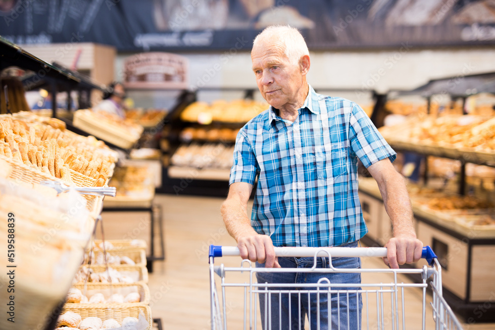 old age senor examines bakery products in the grocery section of the supermarket