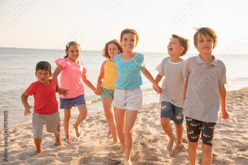 Group of children having fun on the beach, running and smiling. Kids enjoying summer holidays with friends. © Iryna Dincer