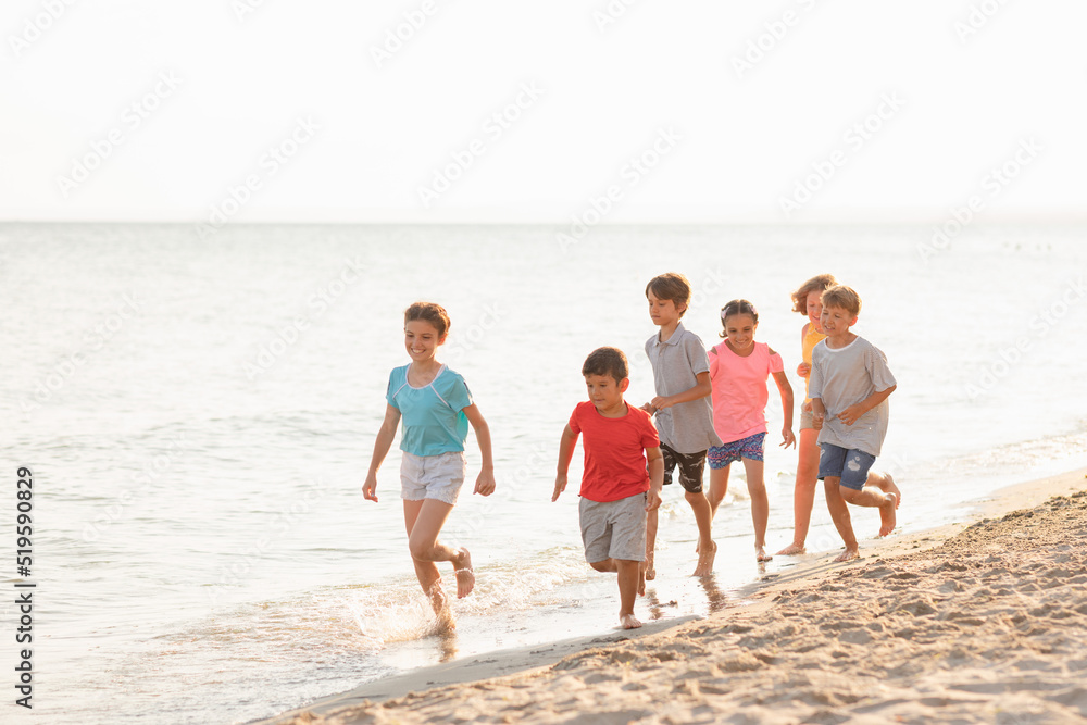 Happy children running on the beach. Cheerful kids having good time at summer holidays. Smiling boys and girls on vacation.