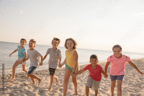 Happy kids running on the beach. Cheerful children having good time at summer holidays. Smiling boys and girls on vacation on seashore.