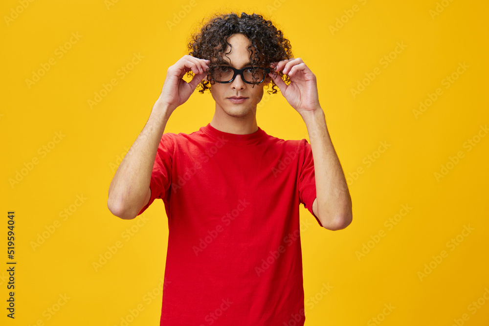 Cute attractive myopic young student man in red t-shirt hold funny eyewear posing isolated on over yellow studio background. The best offer with free place for advertising. Education College concept Cute attractive myopic young student man in red t-shirt hold funny eyewear posing isolated on over yellow studio background. The best offer with free place for advertising. Education College concept