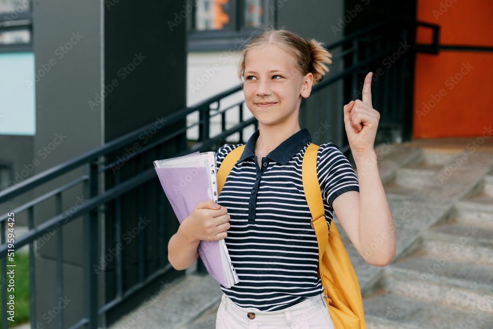 A teenage girl is standing at the stairs with her finger raised up, the girl came up with an idea A teenage girl is standing at the stairs with her finger raised up, the girl came up with an idea