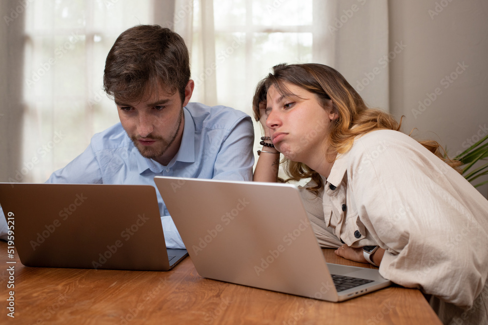 deux jeunes collègues travaillent sur un ordinateur portable. Ils sont fatigués deux jeunes collègues travaillent sur un ordinateur portable. Ils sont fatigués