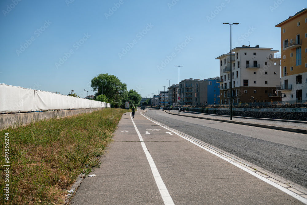 city: road, sidewalk and cycle path in perspective. mono skate in the distance on the bike path. Prediferic urban area, white line of roadways, guides the perspective to infinity. city: road, sidewalk and cycle path in perspective. mono skate in the distance on the bike path. Prediferic urban area, white line of roadways, guides the perspective to infinity.