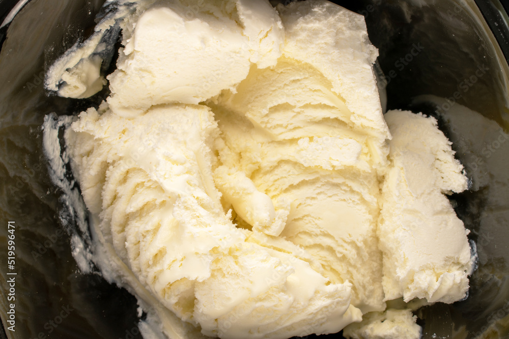 Several scoops of cold white ice cream in a black ceramic bowl, macro, top view. Several scoops of cold white ice cream in a black ceramic bowl, macro, top view.