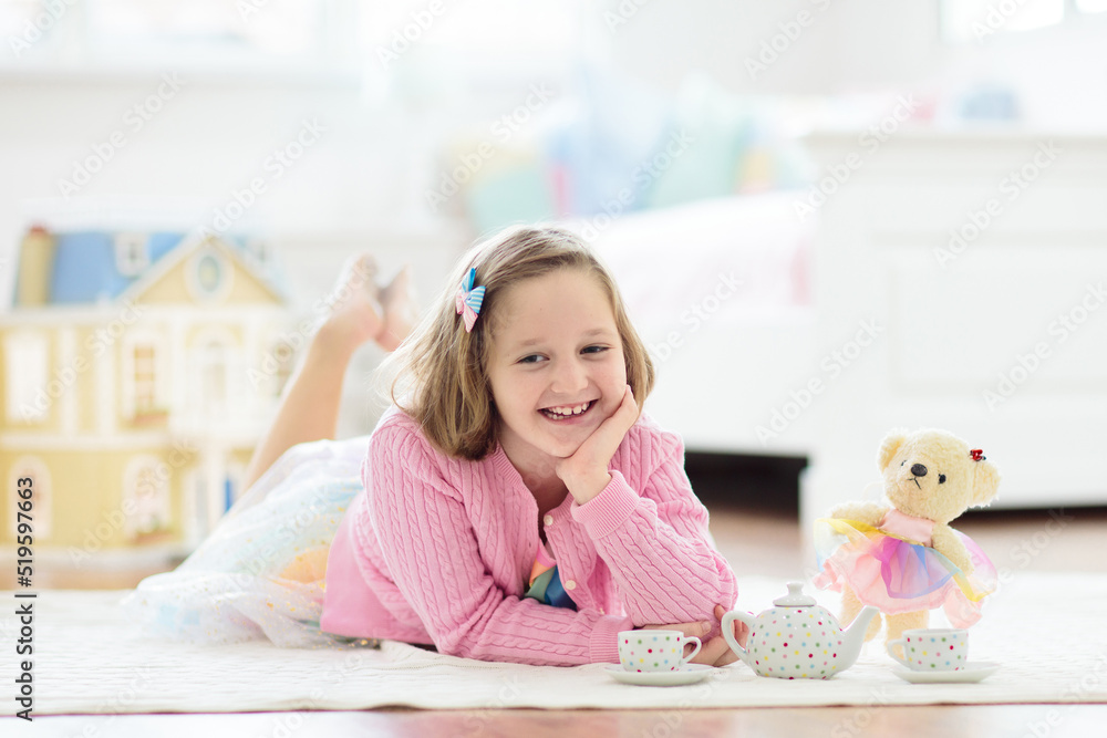Little girl playing with doll house. Kid with toys