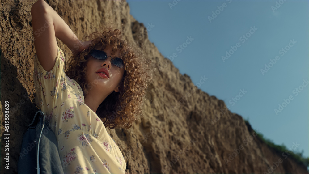Fototapeta premium Seductive model standing lighted sunlight on seashore close up. Woman posing.