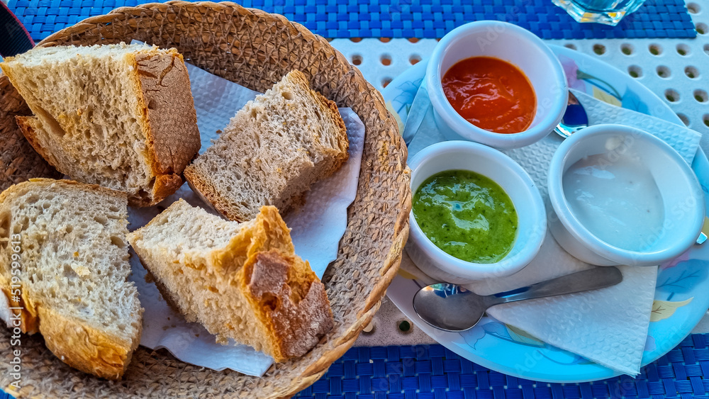 Sauces called Mojo rojo and mojo verde served with white bread in a local restaurant in Los Abrigos, Tenerife, Canary Islands, Spain, Europe, EU. Local traditional food. Appetiser - obrazy, fototapety, plakaty 