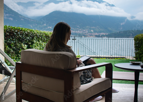 Female Drinking Aperol Spritz and lounging in chair infront of Lake Como in Italy