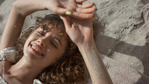 Foto Seductive lady lying beach sand hiding face behind hands closeup