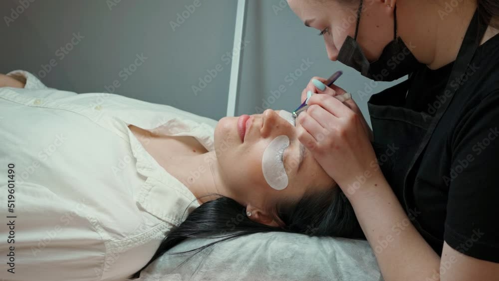 the eyelash extension master bent over the client on the couch and makes the eyelash extension procedure the eyelash extension master bent over the client on the couch and makes the eyelash extension procedure