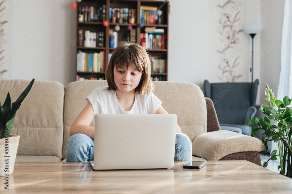 Girl schoolgirl study at home using a laptop. A child watches a webinar or prepares for an exam online. Distance learning for children Girl schoolgirl study at home using a laptop. A child watches a webinar or prepares for an exam online. Distance learning for children