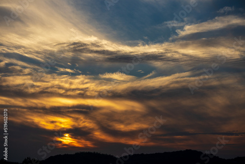 雲に隠れて山の向こうに沈む夕日 © K.TARAKU
