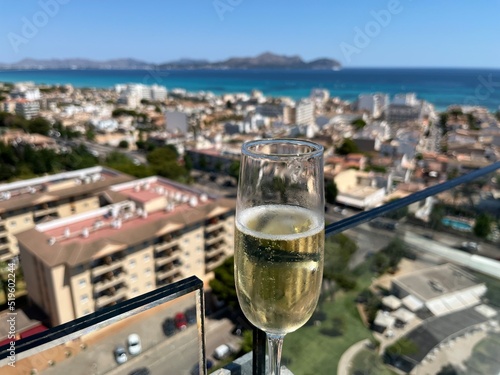 Panorama of the Mediterranean sea and the buildings of Mallorca - Happy life on the road (vacation- holiday) glass of champagne, hand with a glass of champagne