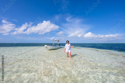 woman in shallow sea with boat