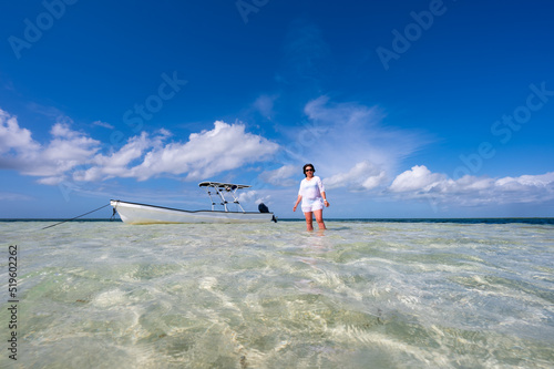 woman in shallow sea with boat