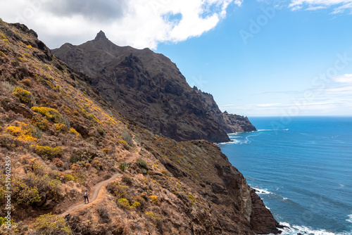 Backpack woman on hiking trail from Afur to Taganana with scenic view of Atlantic Ocean coastline and Anaga mountain range, Tenerife, Canary Islands, Spain, Europe. Looking at Cabezo el Tablero crag © Chris