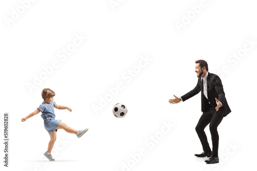 Full length profile shot of a little girl playing a football with her father
