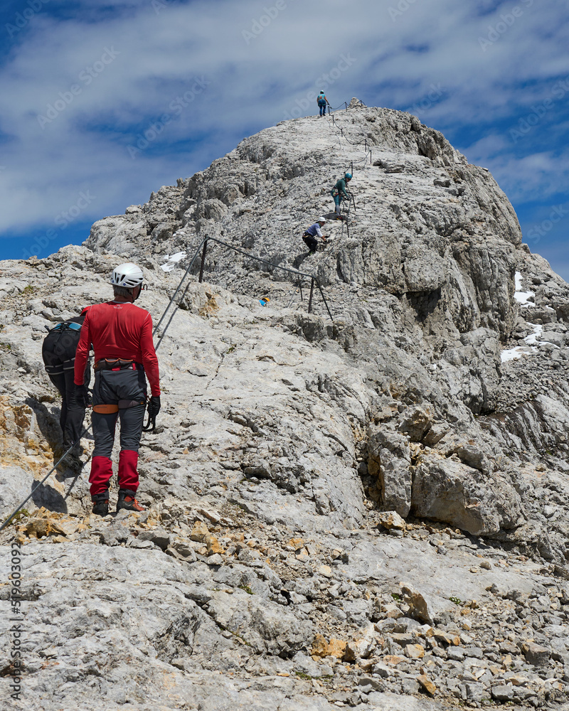 der Bergführer schaut zu wie die Kletterer im Klettersteig aufsteigen, Dachstein, Österreich