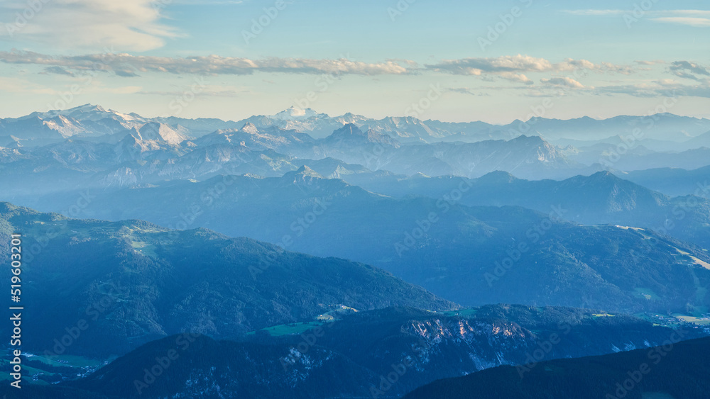 Landscape with distant mountains int the setting sun appearing blue with haze, looking toward the central alpine region from Austria toward Switzerland as seen from the Dachstein Mountains