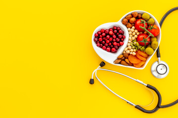 Cholesterol diet concept. Healthy food in heart shaped dish with stethoscope
