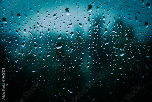 Drops of rain on glass with filter effect retro vintage style. Raindrops on window glass. Selective focus. Rainy city background. Wet glass view of park autumn, abstract background drops on the glass.