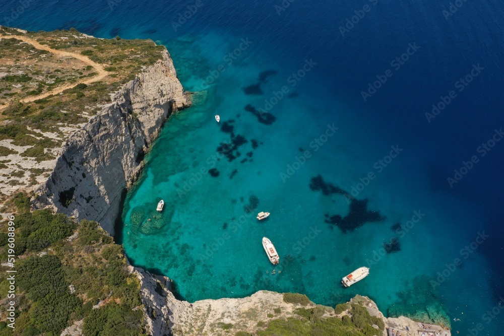 White boats, yachts in blue turquoise ocean lagoon, rocky mountain shore, aerial. High quality image.